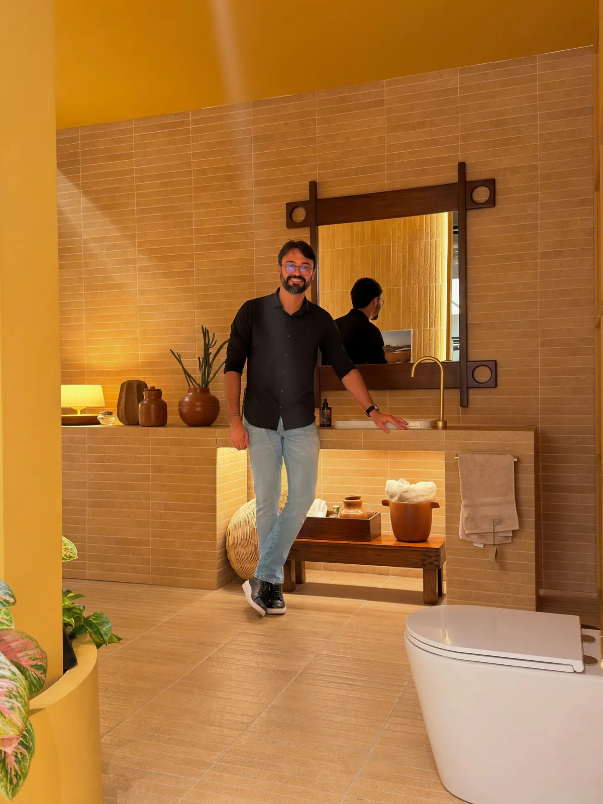 Kaká Pitombo em lavabo entregue, com revestimento em tons de areia e bancada iluminada